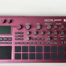 Bordeaux červený sampler KORG electribe sampler MUSIC PRODUCTION STATION. Zařízení obsahuje displej, několik otočných potenciometrů a mřížku šestiдес…
