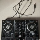 Černý DJ kontrolér značky Numark s dvěma stříbrnými jog-koly. Na přístroji jsou nápisy Numark, PARTY MIX a označení kanálů 1 a 2. Zařízení obsahuje r…