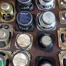 Fotografie zobrazuje skupinu různých reproduktorů v kovových a plastových rámech. Jsou zde dva stejné černé reproduktory s nápisem SENCOR MODEL: SP-2…