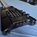 Černá elektrická basová kytara s lesklým povrchem. Na snímači je viditelný nápis „Seymour Duncan“. Ovládací panel obsahuje tři černé vřetenové knofík…