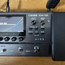 Černý kytarový efektový procesor s integrovaným expresním pedálem. Na přístroji je nápis BOSS GX-10 a logo A.I.R.D. Displej zobrazuje text GX-10 GUIT…