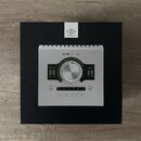 Stříbrné audio rozhraní s nápisem apollo twin | x a logem UNIVERSAL AUDIO na přiloženém štítku. Přístroj má velký centrální ovládací knoflík, LED ind…