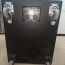 Černý subwoofer s texturovaným povrchem, osazený čtyřmi kolečky. Na zadním panelu je bílý nápis DYNACORD Sub 118, označení INPUT a symbol CE. Povrch…