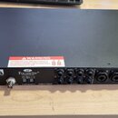 Černý rackový audio interface s kovovým povrchem. Na zadním panelu je bílé logo Focusrite® a nápis Designed in England. Jsou zde vidět konektory pro…
