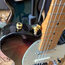 Detail elektrické kytary s tmavým, přechodovým lakem a bílým pickguardem. Na horní hraně korpusu jsou vidět dva zlaté kovové prvky, pravděpodobně pot…