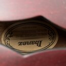 Fotografie zachycuje vnitřní štítek nástroje viditelný skrze otvor v červeném korpusu. Na oválném béžovém štítku je černý nápis Ibanez a texty MODEL…