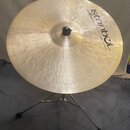 Zlatavý kovový činel umístěný na chromovaném stojanu. Na povrchu je černý nápis „Istanbul“ s hvězdicí a pod ním menší text „Mehmet Handmade Cymbals f…