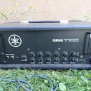 Černý kytarový zesilovač v texturovaném pouzdře s kovovými rohy a úchyty. Na předním panelu je bílé logo Yamaha a nápis YAMAHA T100. Panel obsahuje p…