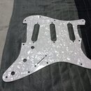 Bílý pickguard s perleťovým efektem určený pro elektrickou kytaru. Povrch je hladký a reflexní, bez viditelných značek, log nebo nápisů. Kousek vykaz…