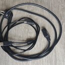 Na fotografii jsou dva černé kabely s různými konektory. Jeden kabel má síťovou vidlici a nečitelný konektor na druhém konci, druhý kabel má USB kone…