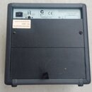 Zadní strana černého elektronického zařízení v plastovém šasi. V horní části je vidět napájecí konektor a nápisy „A“, „CE“ a „PASSPORT“. Na levé stra…