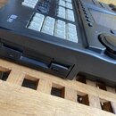 Černý elektronický hudební přístroj s ovládacími tlačítky a otočným knoflíkem. V levém horním rohu je bílé logo GX a nápis "digital". Na boku přístro…