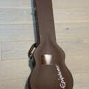 Hnědý tvrdý kufýr na kytaru s rukojetí. Na spodní části je bílý nápis Epiphone. V horní části těla se nachází čtvercová náleplka s nečitelným textem.…
