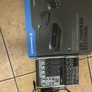 Na fotografii je modrá krabice s nápisy WIRELESS HEADMIC SET, EASY TO USE, EXCELLENT FOR LIVE SOUND a XS WIRELESS 1 spolu s logem SENNHEISER. Pod kra…