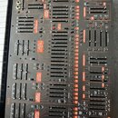 Černý analogový syntetizátor s množstvím posuvníků, tlačítek a zapojovacích konektorů. Na panelu je v levém dolním rohu nápis 2800 a logo behringer.…