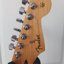Zadní strana hlavy elektrické kytary z přírodního dřeva. Na povrchu je nápis „ORIGINAL Contour Body“ a pod ním vertikálně napsané „Fender® STRATOCAST…