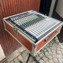 Míchací pult umístěný v transportním kufru s hnědými stěnami a hliníkovým profilem. Na horním panelu přístroje je v pravém horním rohu logo STEINBERG…
