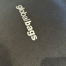 Detailní záběr na černý textilní povrch s texturou tkaniny. Na povrchu je bílý nápis globalbags. Materiál vypadá čistě a v dobrém stavu.
