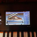 Detailní pohled na ovládací panel digitálního klavíru s barevným displejem. Na obrazovce je zobrazeno menu s nápisy PROGRAM, SGX-2:Main a A016: Brigh…