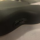 Černá kytara s matným povrchem a světlým lemováním. Na boku korpusu je umístěn ovládací panel s nápisy EQ, BASS, MID, TREBLE, VOLUME, GAIN, DRIVE a T…