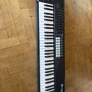 Černý MIDI kontrolér s klaviaturou. Na pravé straně je umístěno několik řad tlačítek, osm otočných potenciometrů a v horní části dva posuvníky. V pra…