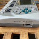 Stříbrný elektronický hudební přístroj s displejem a řadou tlačítek, z nichž čtyři jsou tyrkysově zelené. Na horní hraně je nápis QY70 a vpravo u tla…