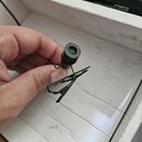 Černý klopový mikrofon s kovovou svorkou. Na těle mikrofonu je viditelné malé číslo 2. V horní části je mřížka s vnitřním tlumicím materiálem. V poza…