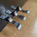 Tři kovové strmenky na prsty pro smyčcový nástroj v stříbrné barvě. Jsou vyrobeny z kovu s matným povrchem a mají ergonomicky zakřivený tvar. Na spod…