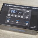 Kartonová krabice s černým potiskem, na které je zobrazen efektový procesor. Na krabici jsou nápisy GT-1000CORE GUITAR EFFECTS PROCESSOR a logo BOSS.…