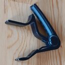 Černý kovový držák na nástroj s kloubovým mechanismem. Povrch vykazuje mírné známky opotřebení a drobné oděrky. Na předmětu nejsou viditelné žádné zn…