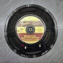 Fotografie znázorňuje zadní stranu černého reproduktoru. Uprostřed je štít s nápisy „SPECIALLY DESIGNED FOR Fender MUSICAL INSTRUMENT COMPANY“, „MFD.…
