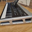Digitální klavír s černými a bílými klávesami a stříbrným plastovým rámem. Na pravé straně horního panelu je nápis CASIO. Nástroj obsahuje displej, n…