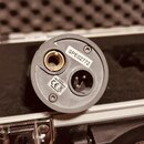 Detailní pohled na spodní část šedého mikrofonu v přenosném kufru. Na povrchu jsou vidět dva nápisy: bílá nálepka s označením SPE02772 a štítek s tex…