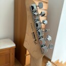 Fotografie zachycuje zadní stranu hlavy kytary z přírodního světlého dřeva. Na dřevě jsou vyryty nápisy Y1905, MADE IN CHINA a logo YAMAHA s obchodní…