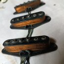Tři elektrické snímače typu single-coil s oranžovými cívkami a černými plastovými základnami. Snímače mají kovové pólové šrouby a jsou připojeny k če…