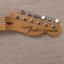 Fotografie zachycuje hlavu elektrické kytary z přírodního dřeva s šesti chromovanými ladičkami. Na dřevě je černý nápis Fender® TELECASTER. Povrch dř…