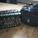 Na fotografii je kytarový procesor s ovládacím pedálem a přivázaným transportním kufrem v tmavě šedé barvě. Na horním panelu pedálu je nápis PROFILER…