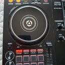 Černý DJ kontrolér s velkým jog-colem uprostřed. Na přístroji je nápis PERFORMANCE DJ CONTROLLER DDJ-400 a logo rekordbox. V dolní části jsou čtyři č…