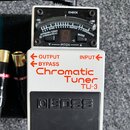 Bílý kytarový pedál s černým displejem a černým stupňovitým spínacím pedálem. Na horní části je nápis CHECK a displej s označením 3 2b BASS 6 5 4 3 2…