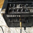 Černý kytarový kombozesilovač značky nux, model MIGHTY 8. Na horním panelu jsou ovládací knoflíky s popisky DELAY/REVERB, EFX a EQUALIZER (TREBLE, MI…