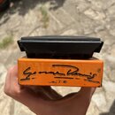 Kytarový efekt pedál v oranžovém kovovém těle s černým plastovým stomečem. Na přední straně je černý nápis „Game Danelectro“ a symbol ®. Povrch pedál…