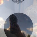 Průhledná bicí blana s černým kruhovým tlumičem v centru. V horní části je černý nápis REMO pod logem ve tvaru koruny a text CONTROLLED SOUND® CLEAR.…