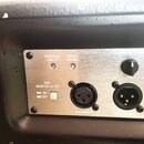 Detail zadního panelu černého reproduktoru s kovovým ovládacím panelem stříbrné barvy. Na panelu jsou nápisy POWER ON/ LIMITER, SIGNAL/ THERMAL, 90Hz…