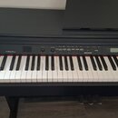 Černý digitální piano s bílými a černými klávesami. Na levé straně ovládacího panelu je bílý nápis MEDELI. Panel obsahuje řadu tlačítek, ovladačů a m…