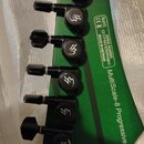 Zelená hlava osmistrunné elektrické kytary s černými ladičkami. Na hmatníku je svislý nápis MultiScale-8 Progressive a dále text SERIAL NUMBER (21)74…