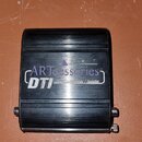 Černý obdélníkový box z kovu s žebrovaným povrchem. Na horní straně je bílý nápis „ART accessories series“ a pod ním označení „DTI“ s menším textem „…