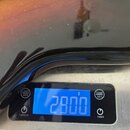 Fotografie zachycuje část tmavého hudebního nástroje s přechodovou barvou (sunburst) položenou na digitální váze. Displej váhy ukazuje hodnotu 2900 g…