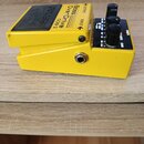 Žlutý basový efekt pedál s černými ovládacími knoflíky. Na horní části je černý nápis Bass OverDrive ODB-3 a logo BOSS. Na boku jsou viditelné nápisy…