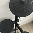 Černá elektronická bicí souprava s gumovými pady. Na horním kruhovém padu je vyražené logo a nápis YAMAHA. Povrchy padů jsou v dobrém stavu bez vidit…