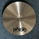 Kruhový kovový činel zlatavé barvy s broušeným povrchem. Na horní části je černý nápis PAISTE a nad ním menší text MADE IN SWITZERLAND. Povrch vykazu…